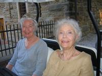 Two elderly women sitting outdoors, smiling at the camera.