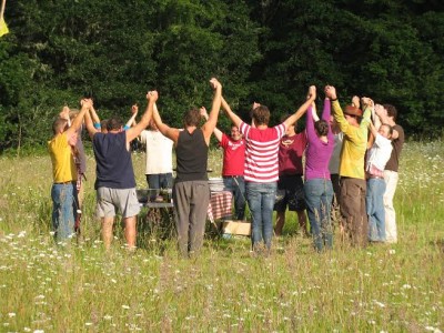 Group of diverse people holding hands in a circle outdoors during daytime.