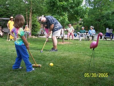 People playing mini golf outdoors in a green park setting.