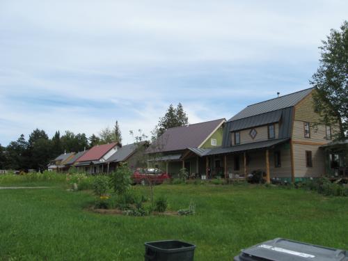 Colorful cohousing homes in a green community setting under a blue sky.