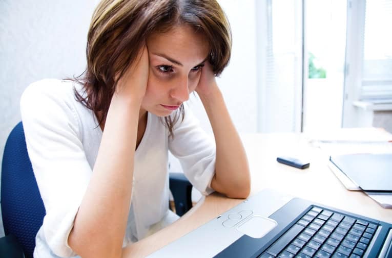 Woman stressed working on laptop at desk for intentional community project.