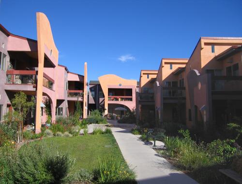 Colorful cohousing community with lush garden and clear blue sky.