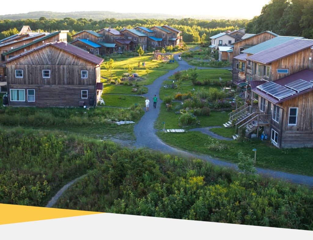 Aerial view of a sustainable intentional community with wooden houses and green spaces.
