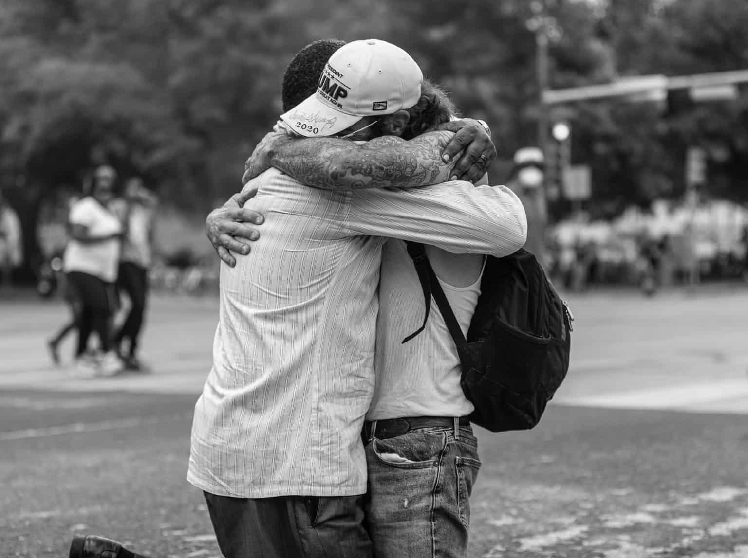 Two people hugging in a public outdoor setting, black and white photo.