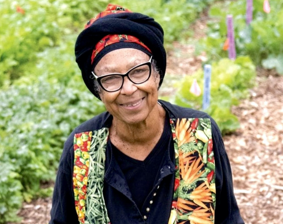 Portrait of Ira Wallace in a garden with colorful plants and flowers.