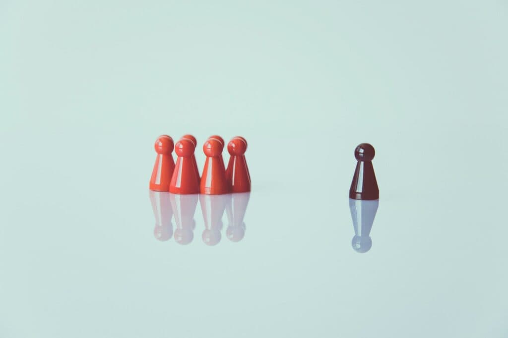 Single black pawn facing four red pawns on a light background.