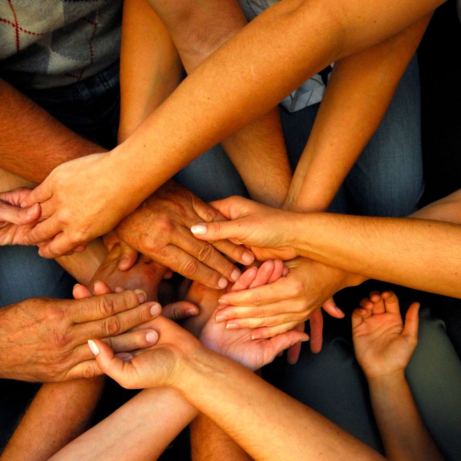 Multiple hands joined together symbolizing community and teamwork.