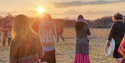 People gathering outdoors during sunset at a community event.