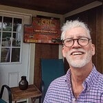 Smiling man with glasses on porch at IC community event.