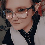 Close-up of a person with elf ears and glasses, smiling, with Foundation for Intentional Community.
