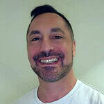 Smiling man in casual white T-shirt, promoting intentional communities.