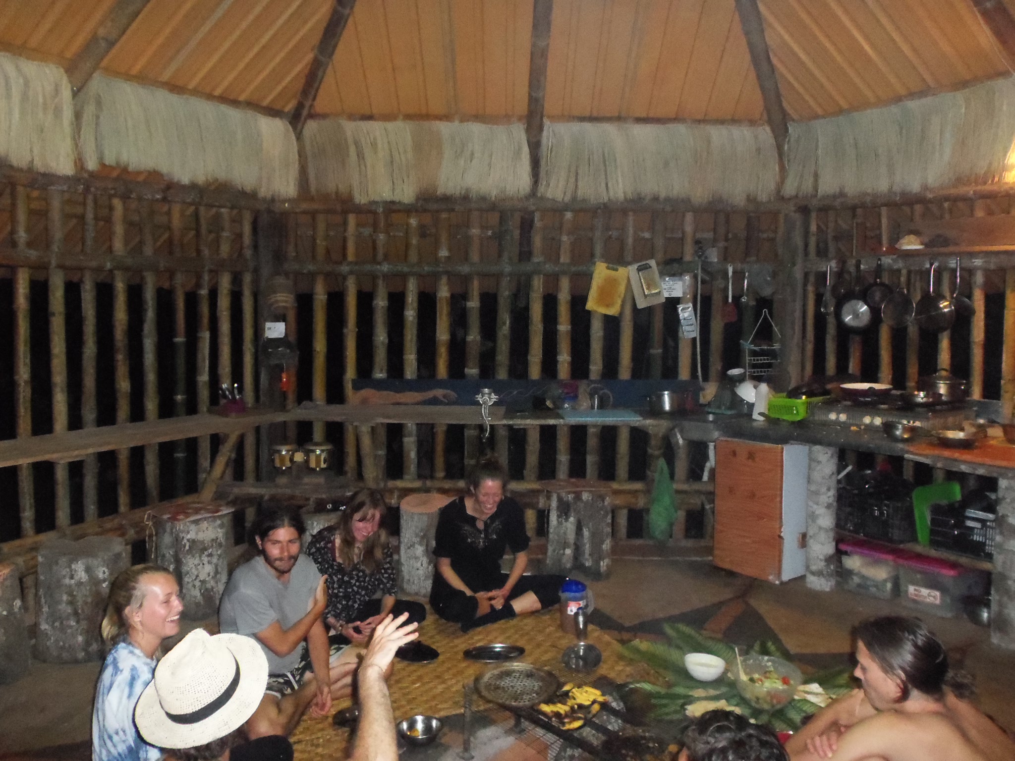 Group of people sitting in a circular formation inside a rustic wooden structure.
