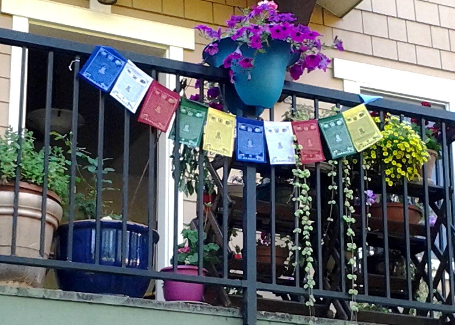Balcony decorated with colorful prayer flags and potted plants.