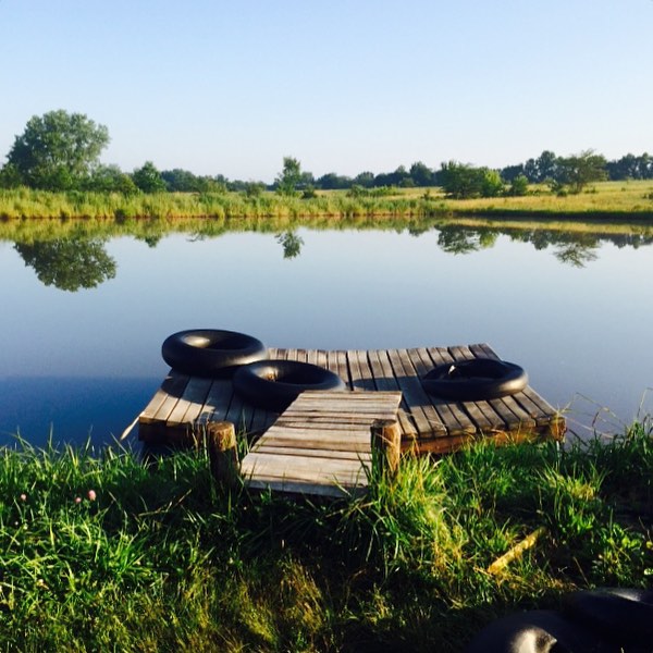 Serene lake view at Dancing Rabbit Ecovillage with a wooden dock and tires.