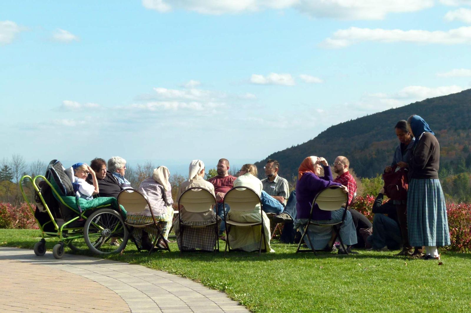 Group of people sitting outdoors in a circle at Platte Clove Bruderhof community.