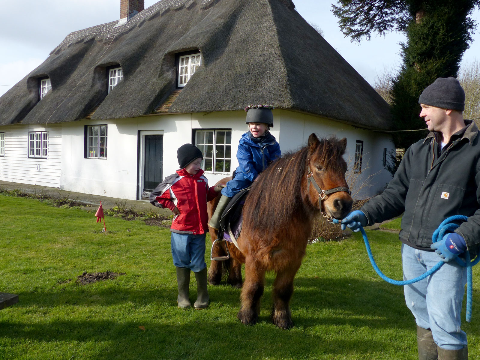 People with a horse in front of a thatched cottage at Beech Grove Bruderhof.