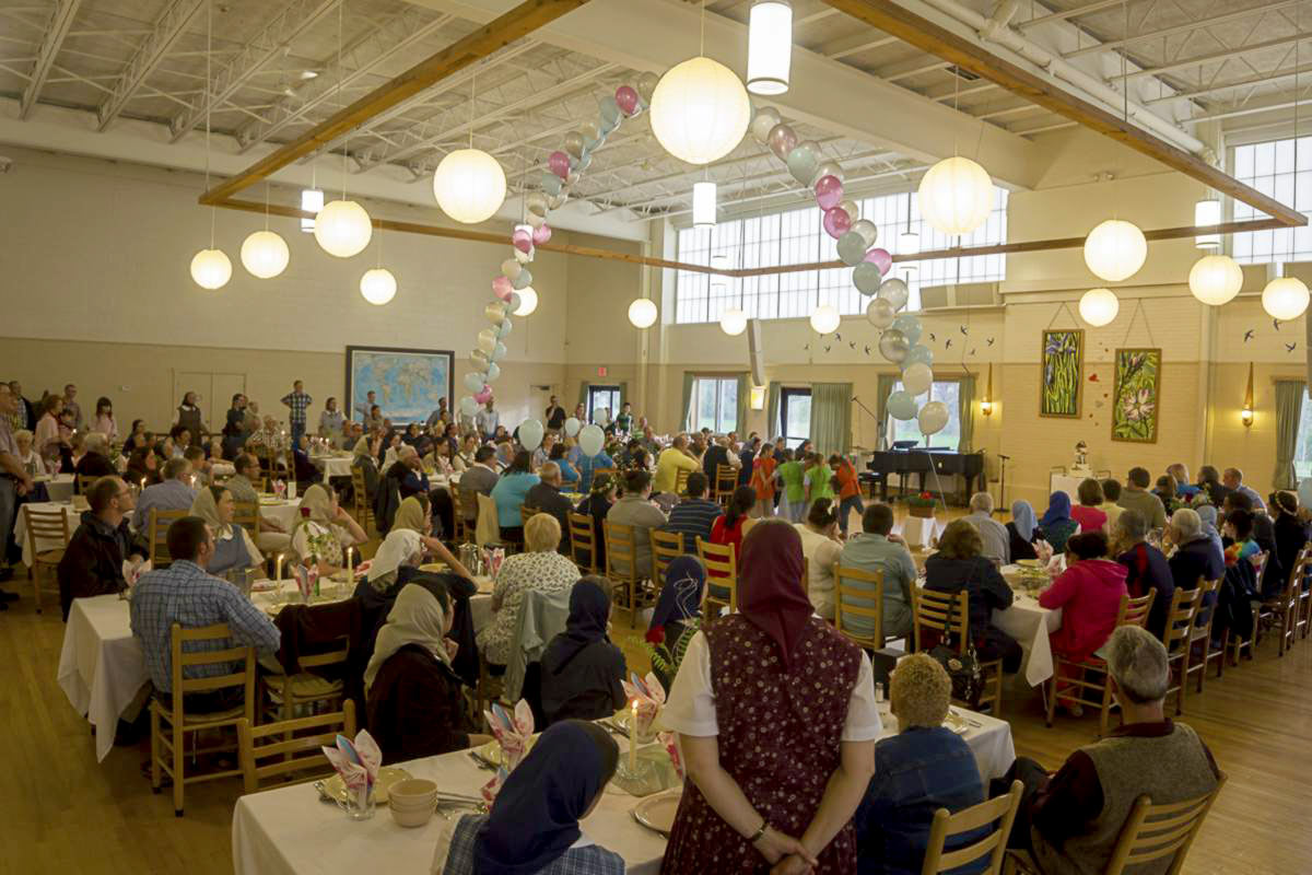 Large community event with people seated at tables in a spacious hall.