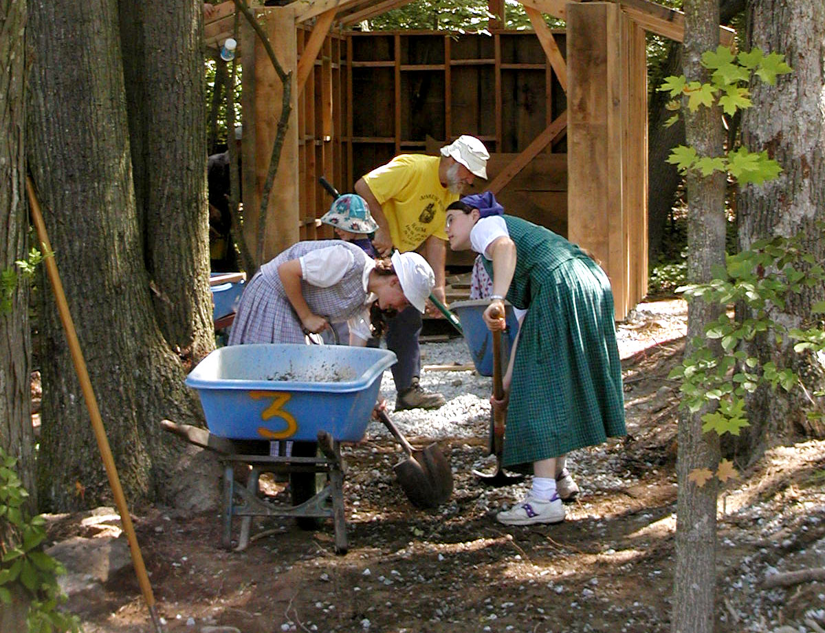 People working together to build a community structure in a wooded area.