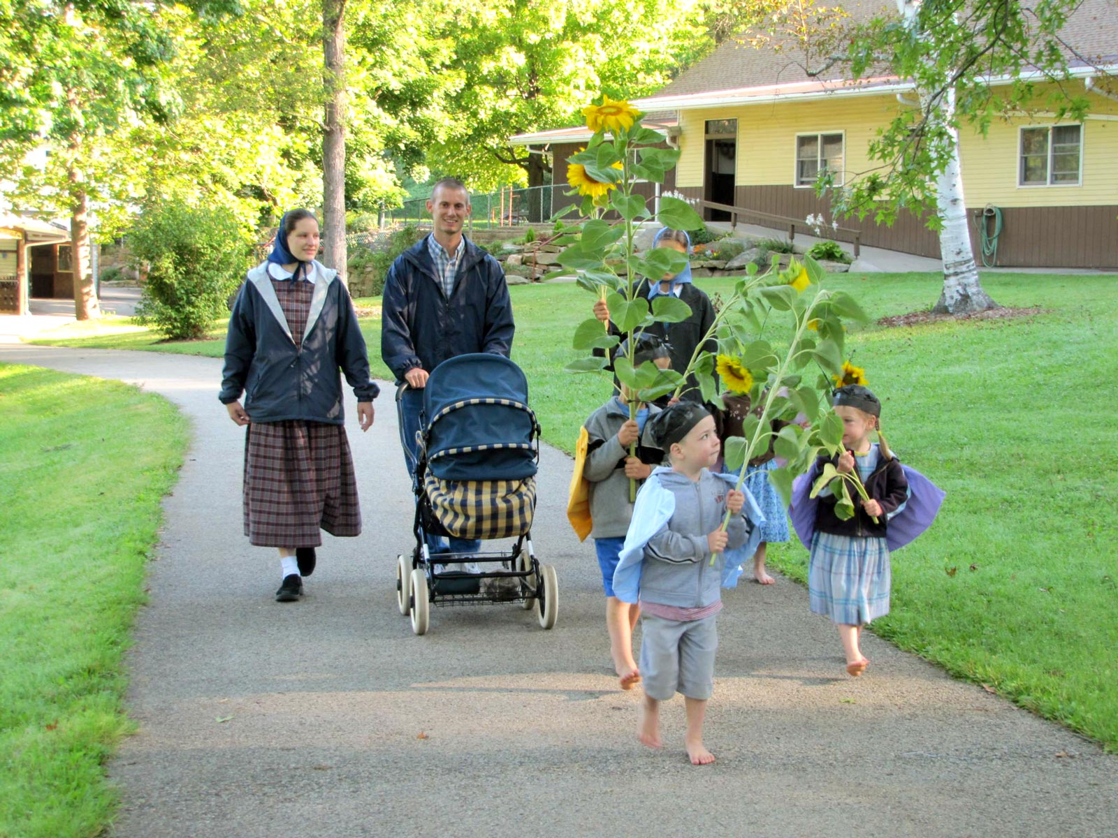 People walking with children and a stroller in a community setting.