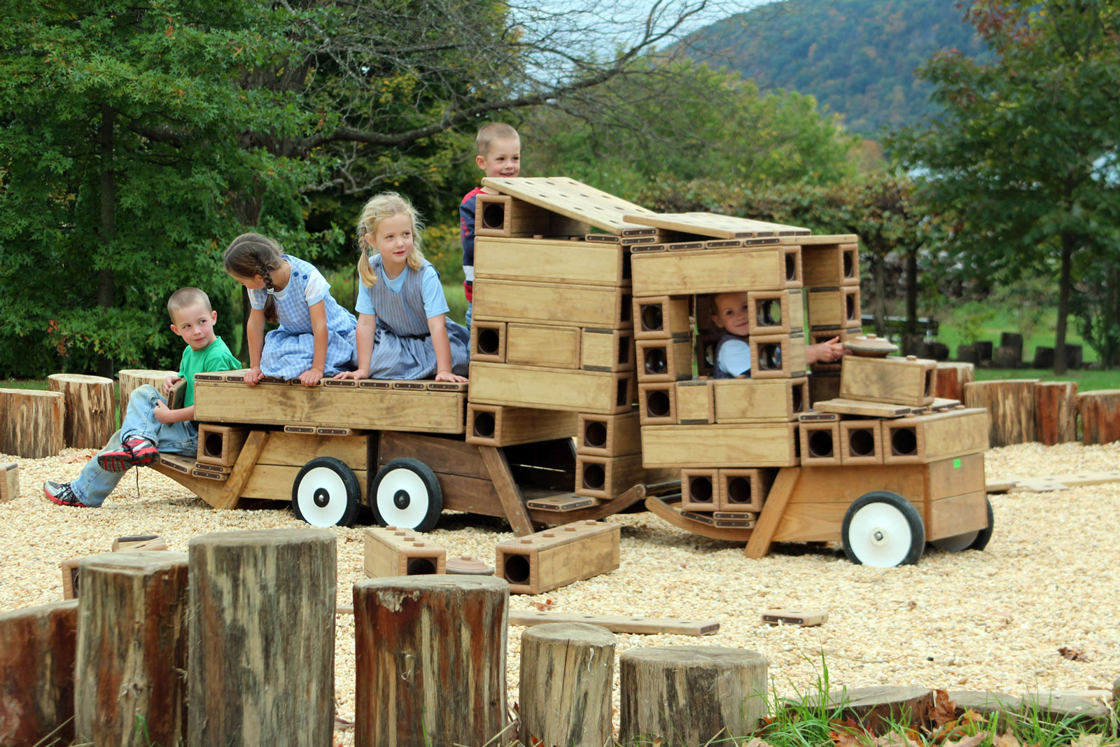 Kids enjoying outdoor play on a wooden train at community playground.