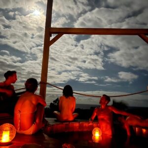 People sitting around a fire pit at Sundari Gardens during evening.