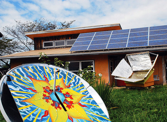 Eco-friendly house with solar panels and colorful outdoor art installation.