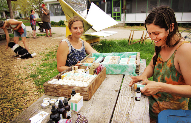 People selling handmade soaps and natural products at a community market.