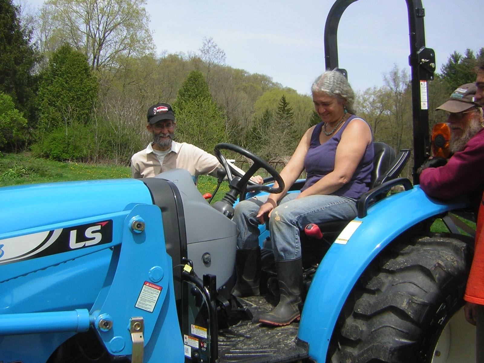People enjoying a tractor ride at a permaculture farm event.