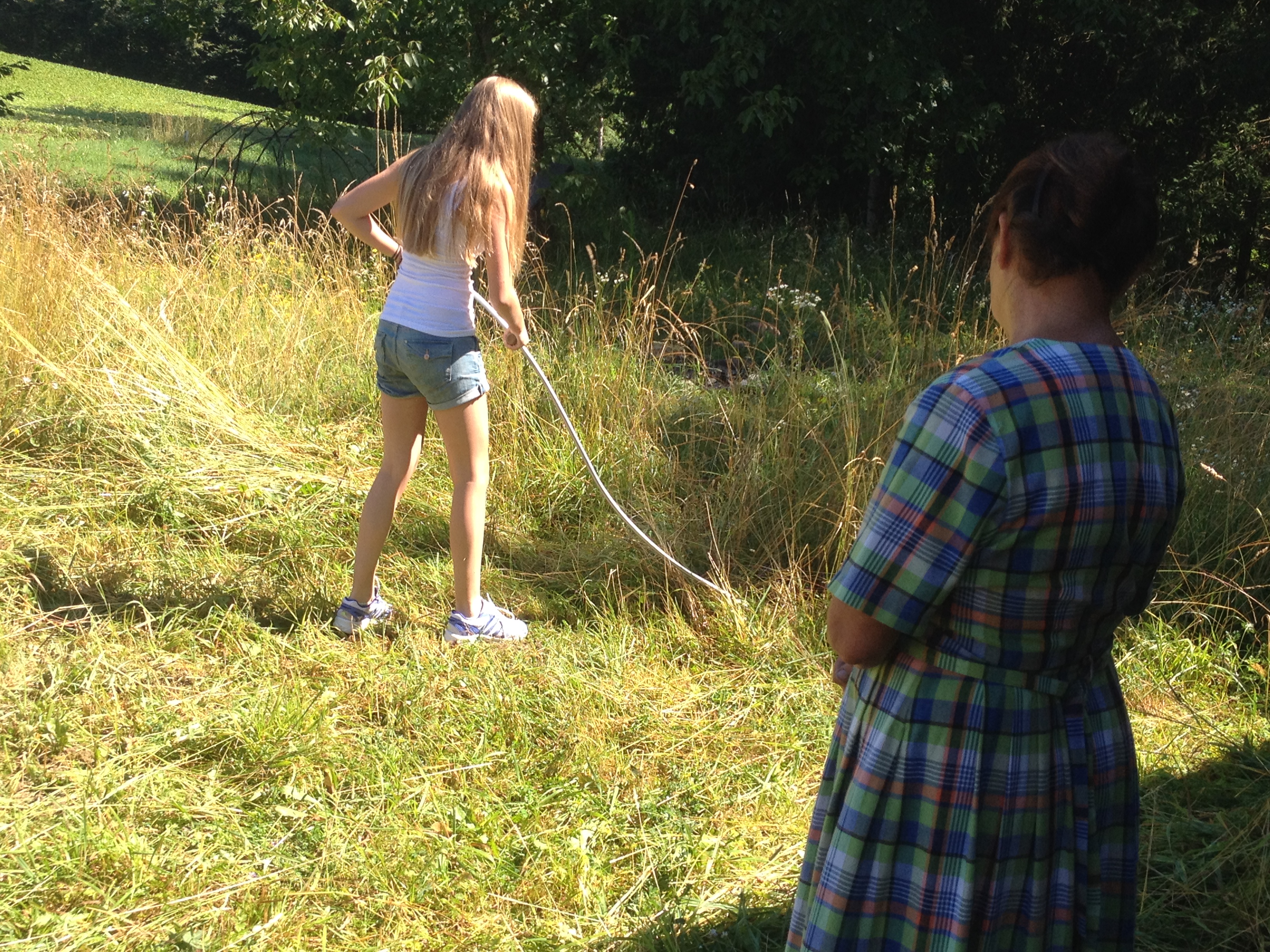 Two women working in a grassy field on a sunny day.