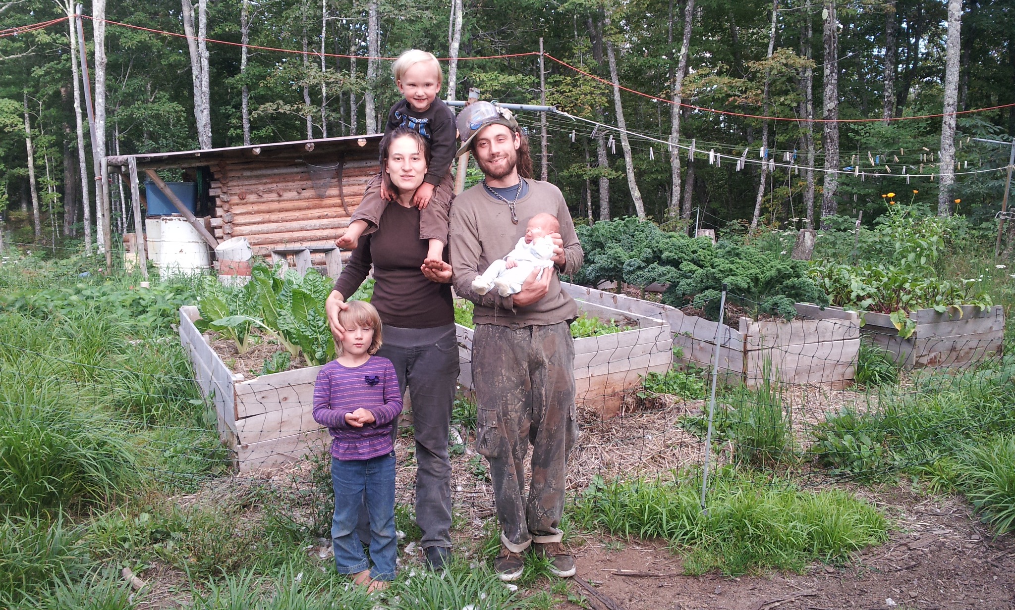Family with children at community garden in a forested area.