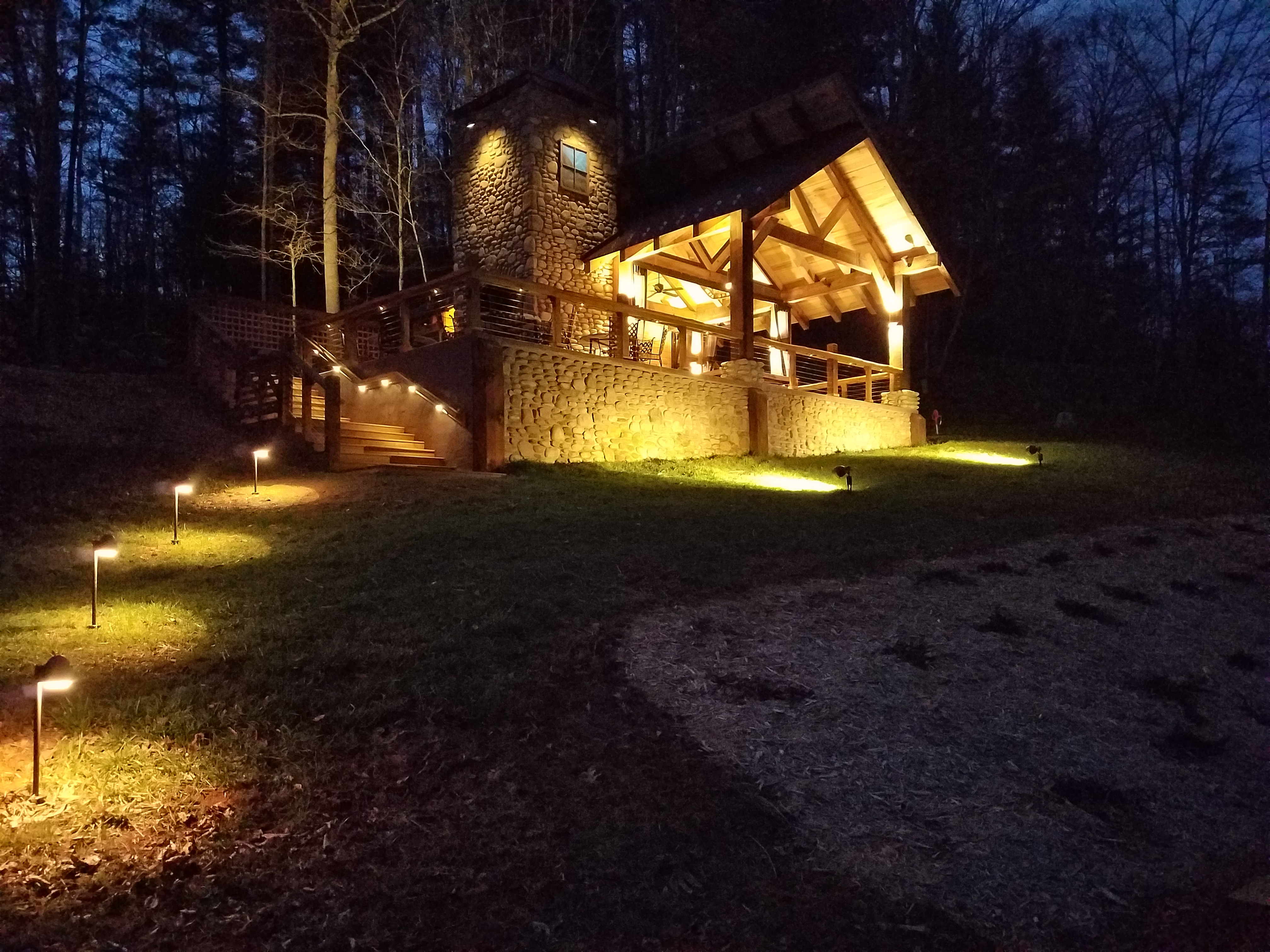 Night view of a lit cabin with outdoor lighting at Asheville Mountain Meadows.