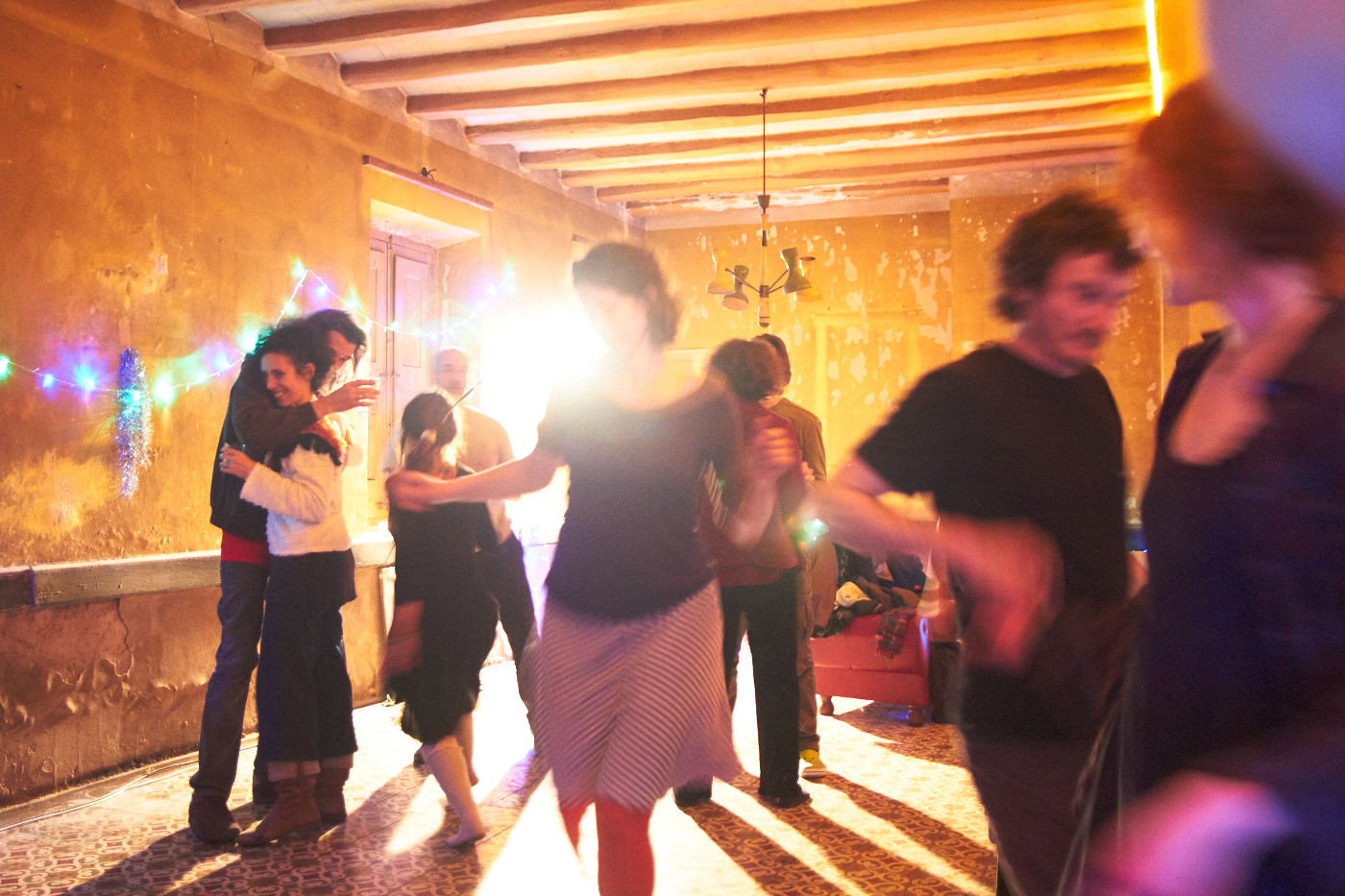 People dancing at a community event in a warmly lit room.