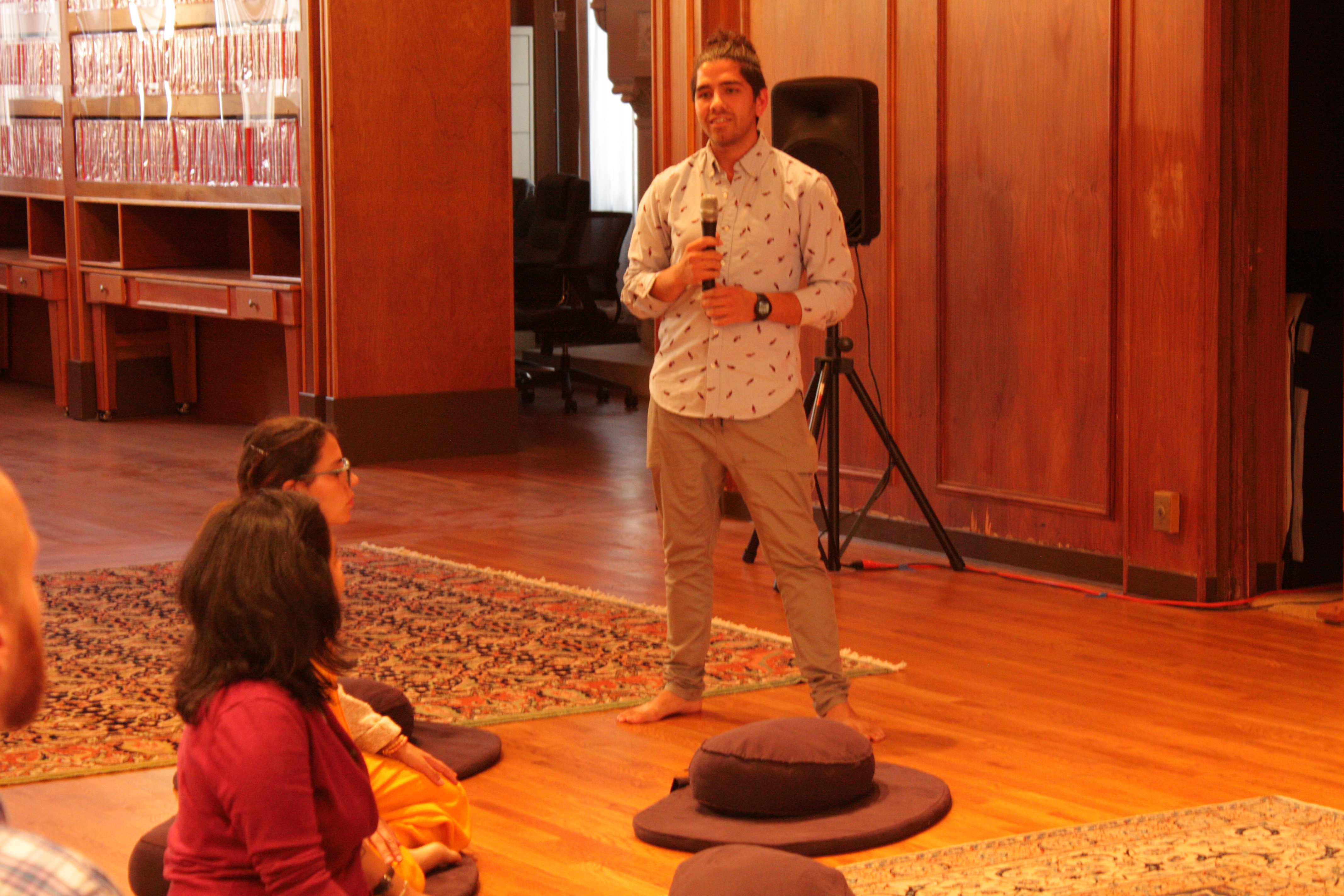 Man speaking to seated audience during community event at Mangalam Center.