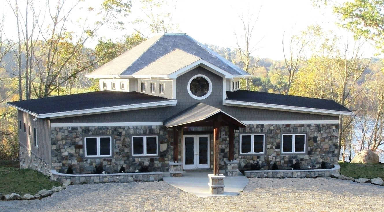 Contemporary community house with stone and wood exterior near a lake.