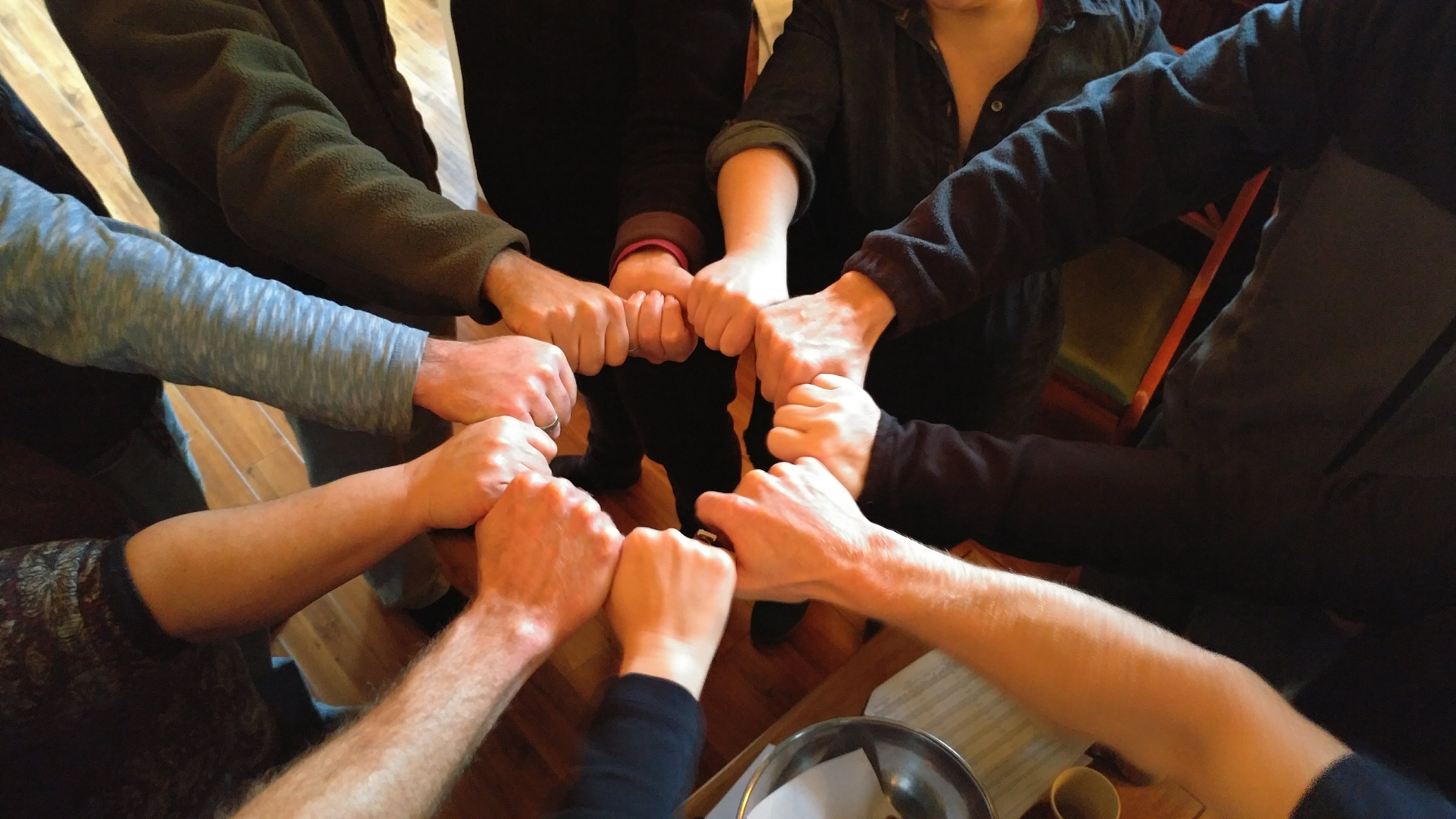 Group of diverse people joining hands in a circle for community unity.