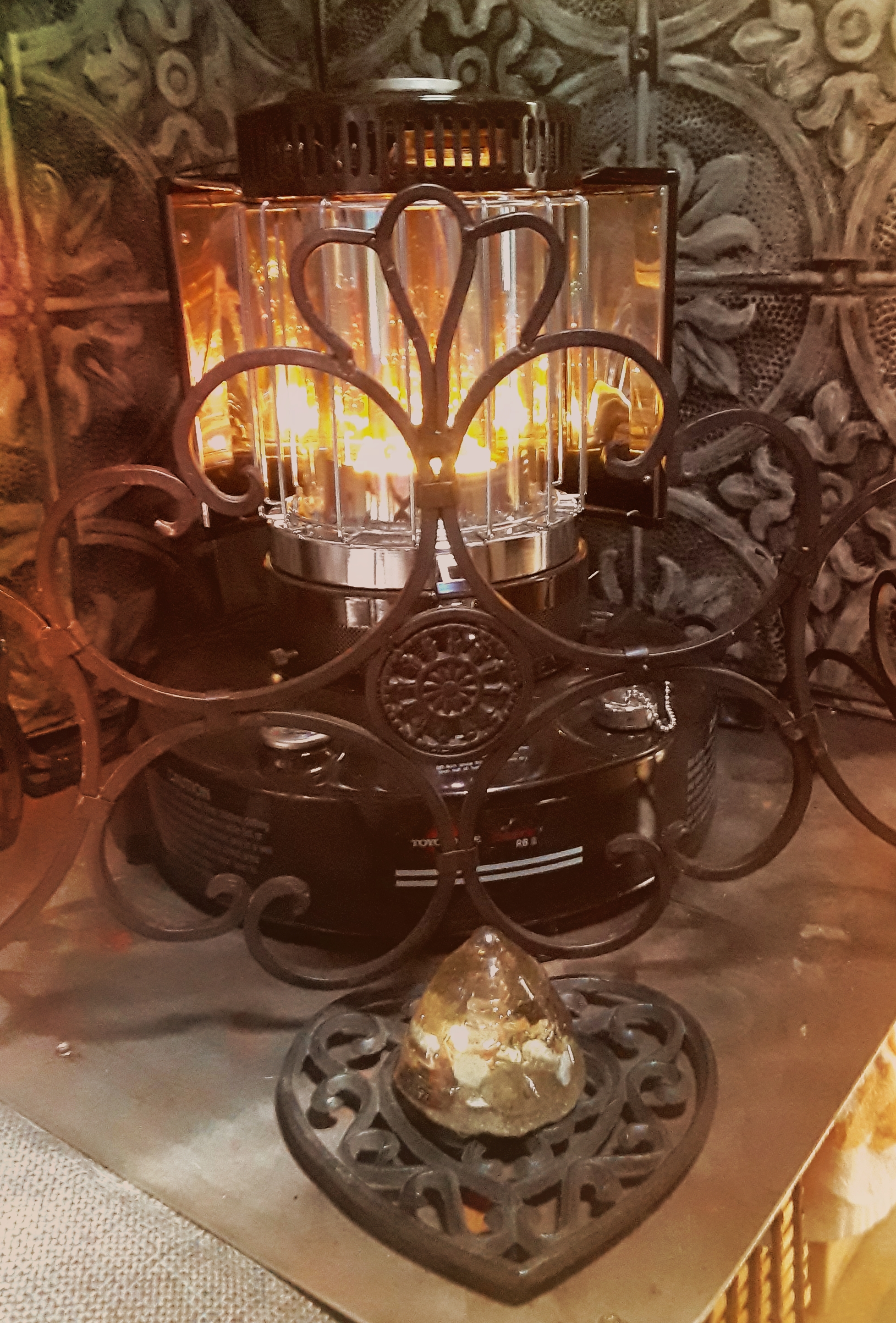 Ornate metal lantern with glass panels and warm candlelight.