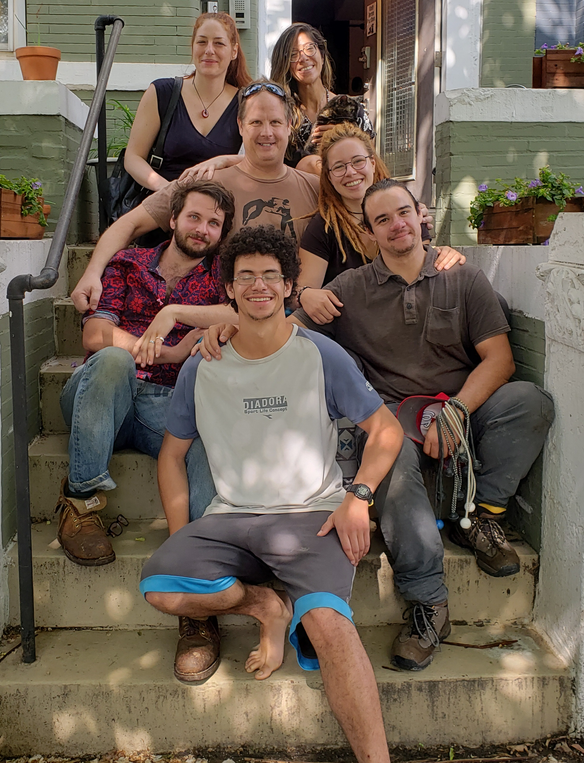 Group of diverse people smiling on steps outside GlowHouse.
