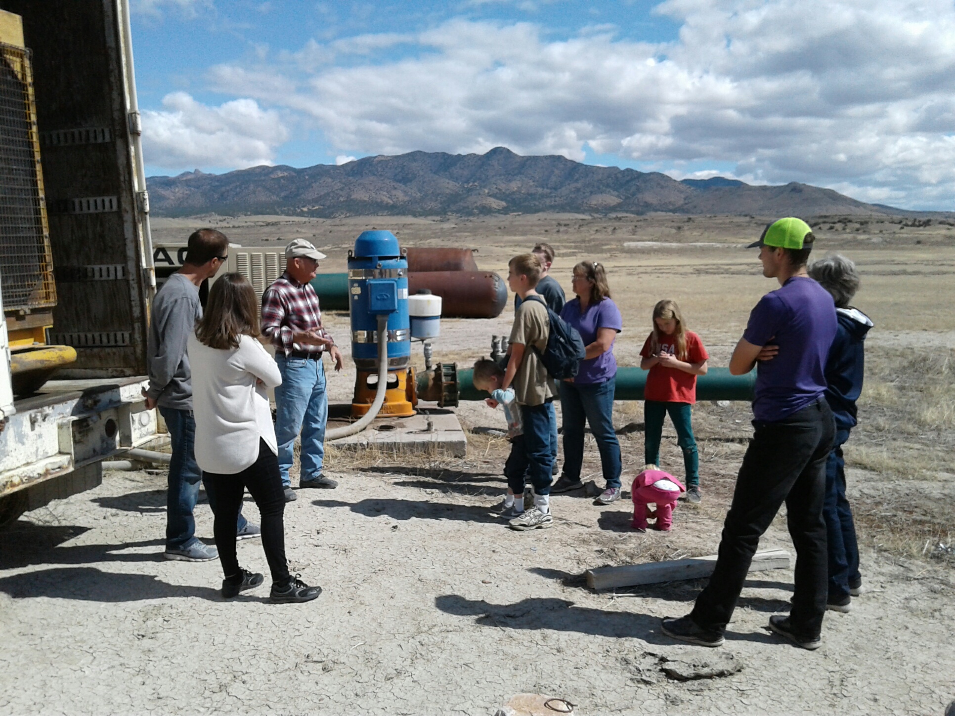 Group of people touring a water system at Riverbed Ranch Homesteading Community.