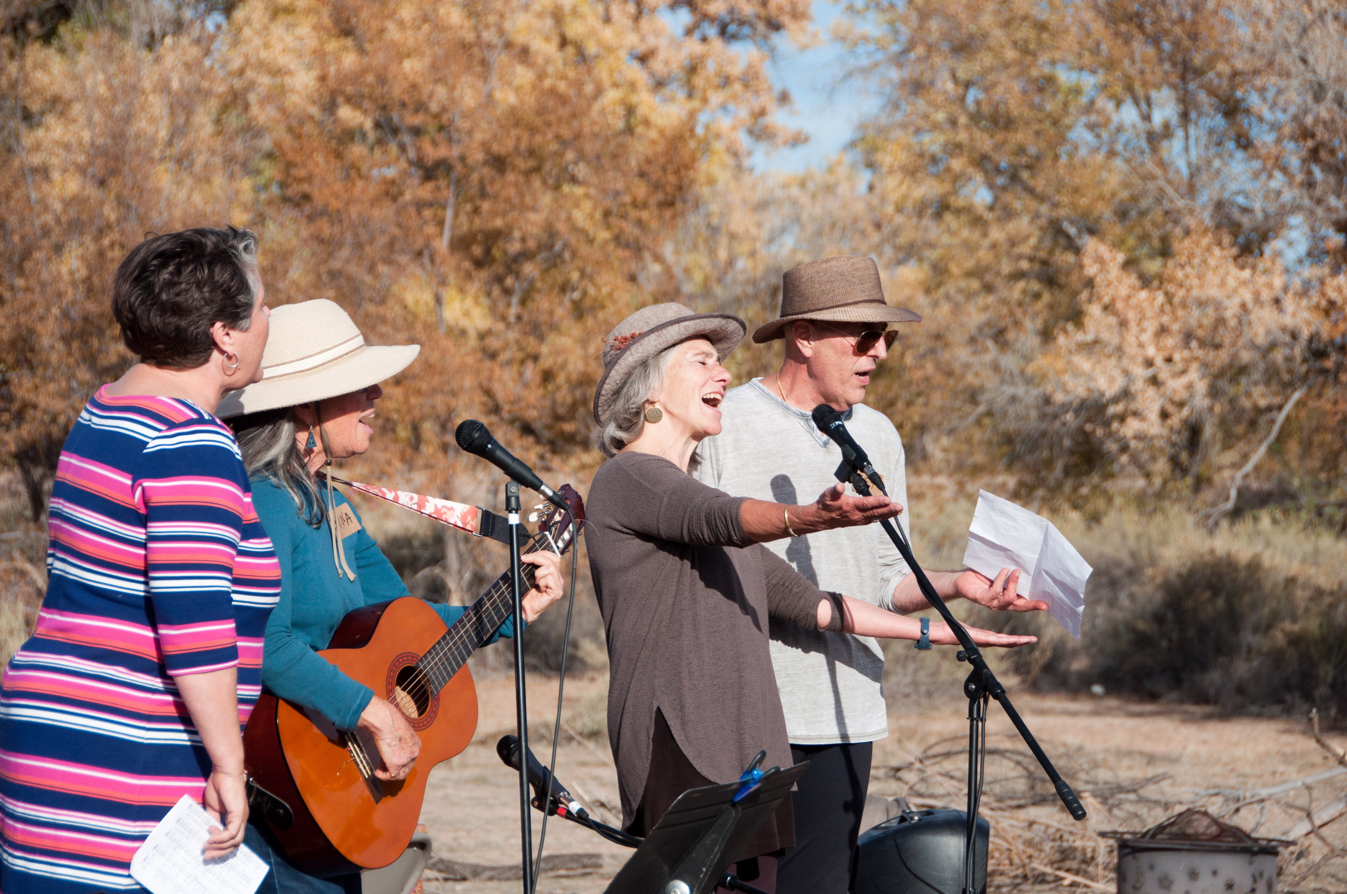 Group of people speaking and playing guitar outdoors at Foundation for Intentional Community.