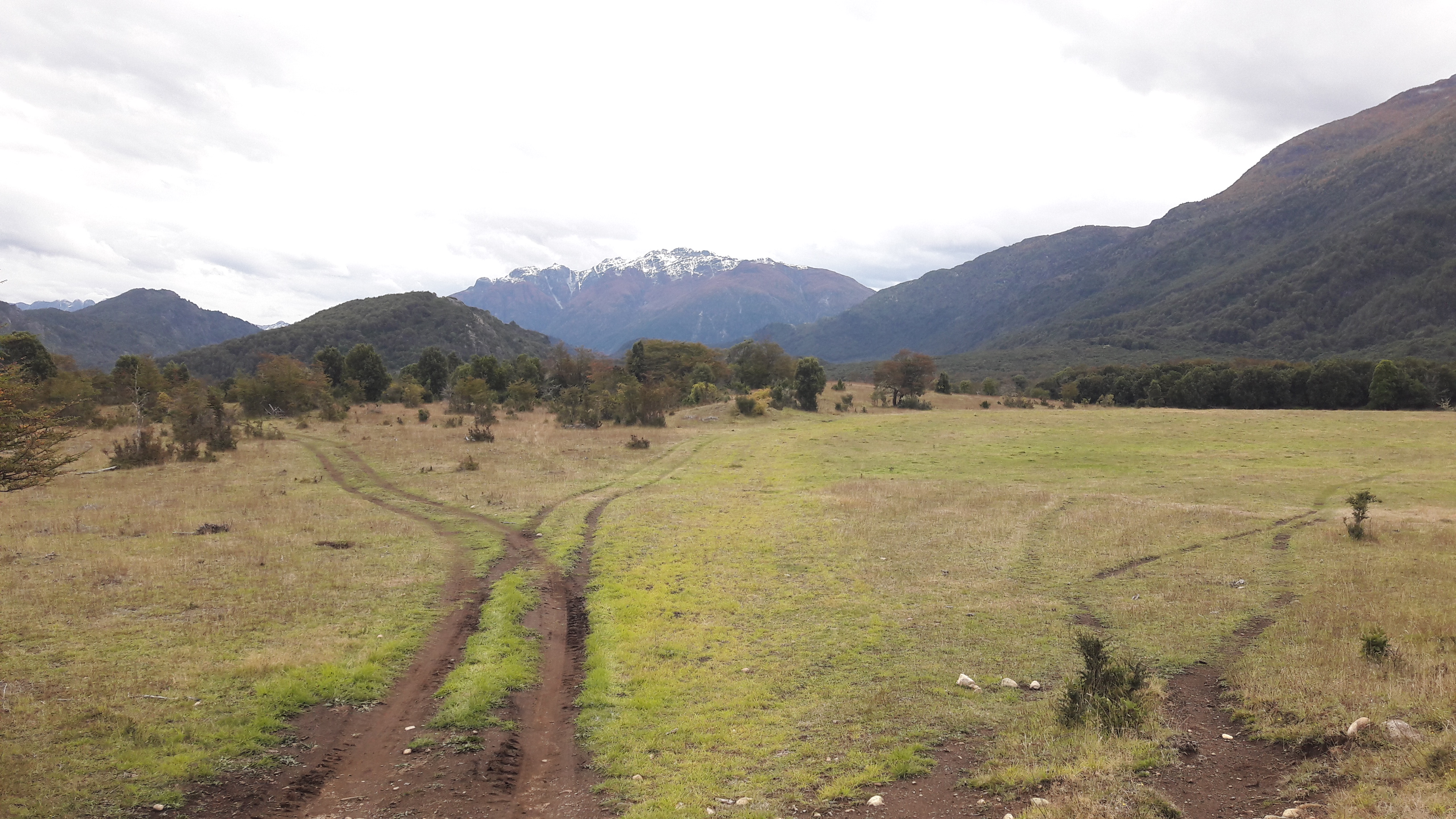 Vast valley with mountain range and cloudy sky in the background.