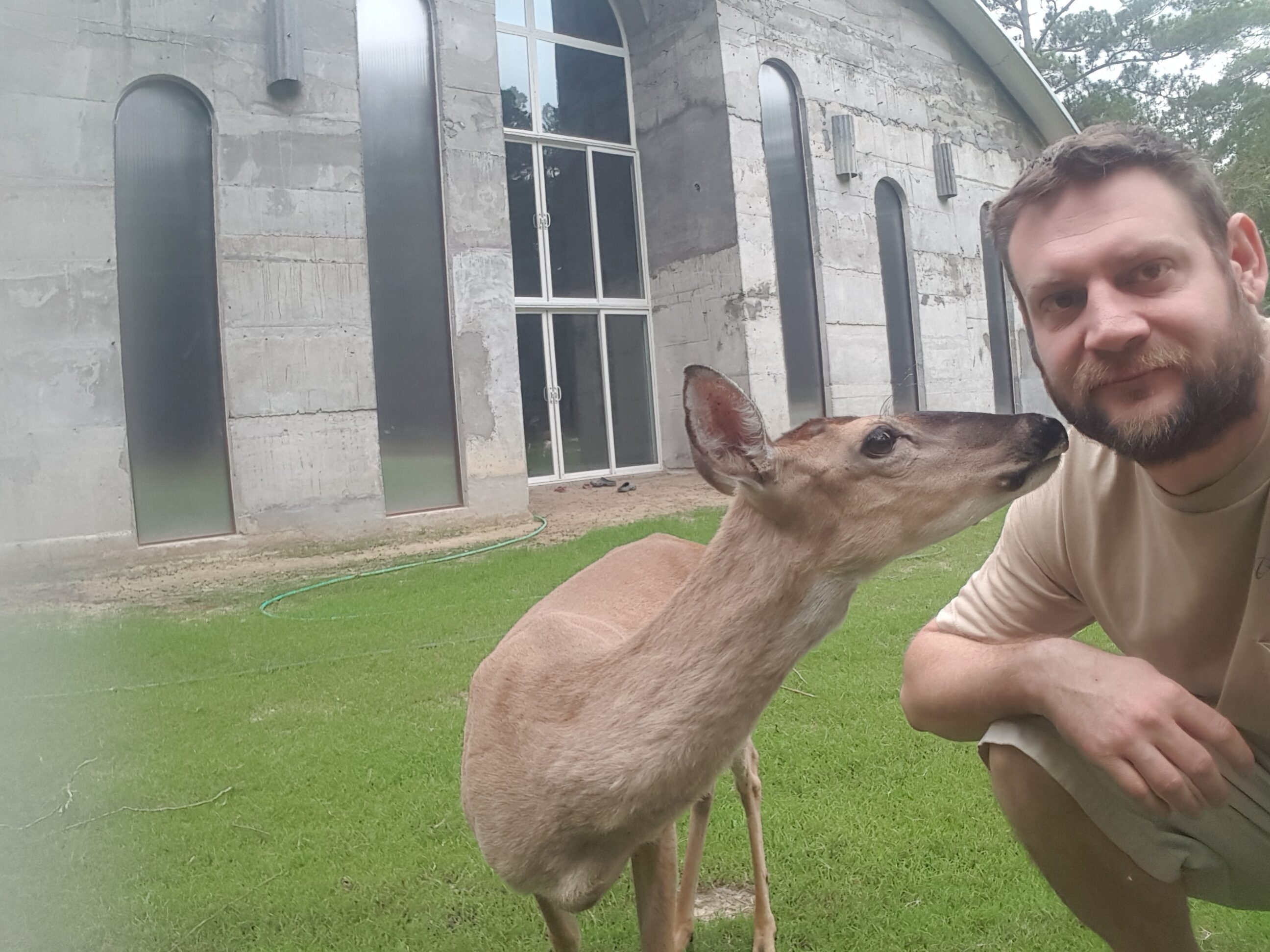 Man with deer in front of modern building at Imladris community.