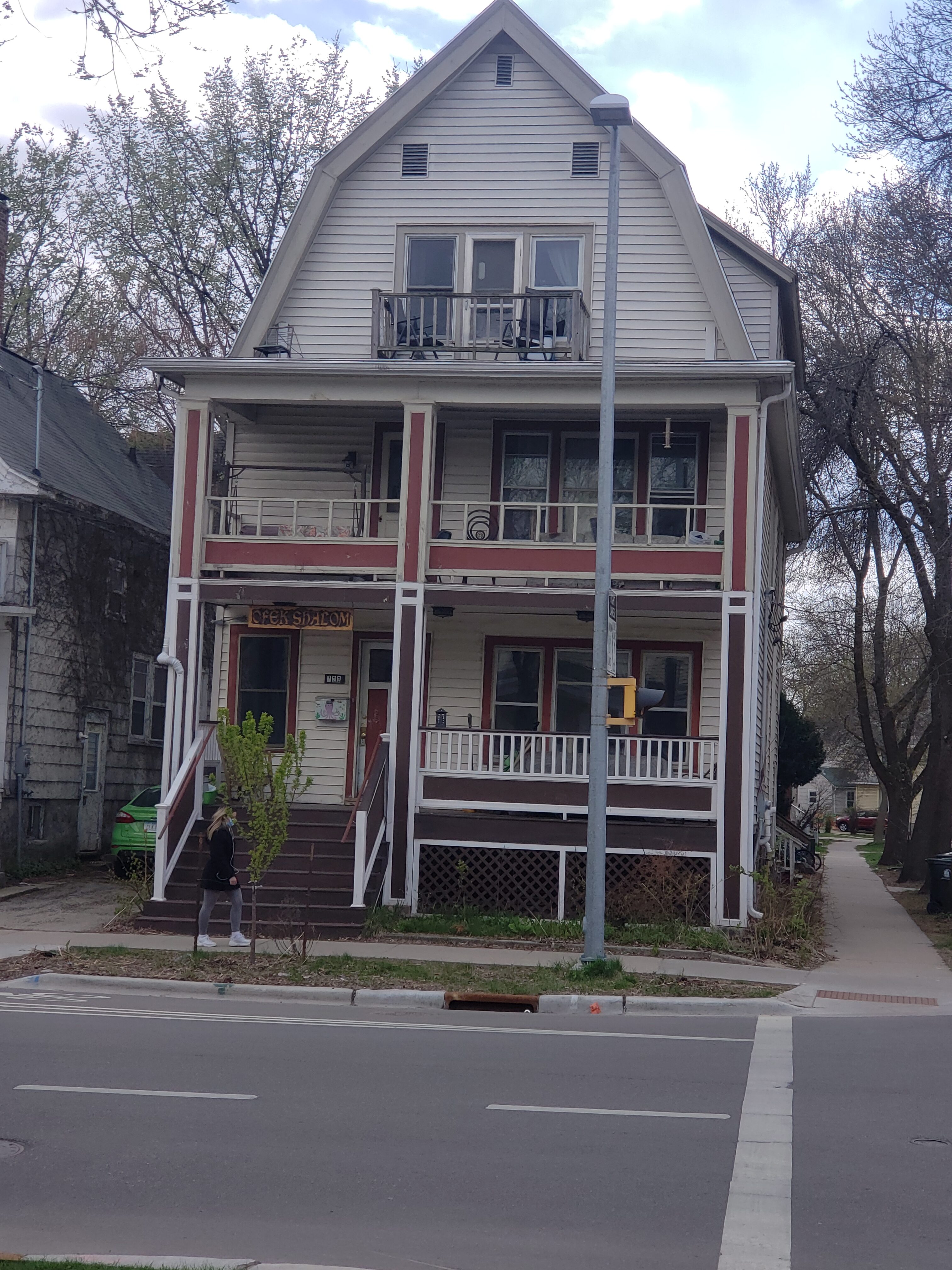 Multi-story community house with balconies and trees in front.