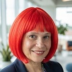 Woman with vibrant red hair smiling at the Foundation for Intentional Community event.