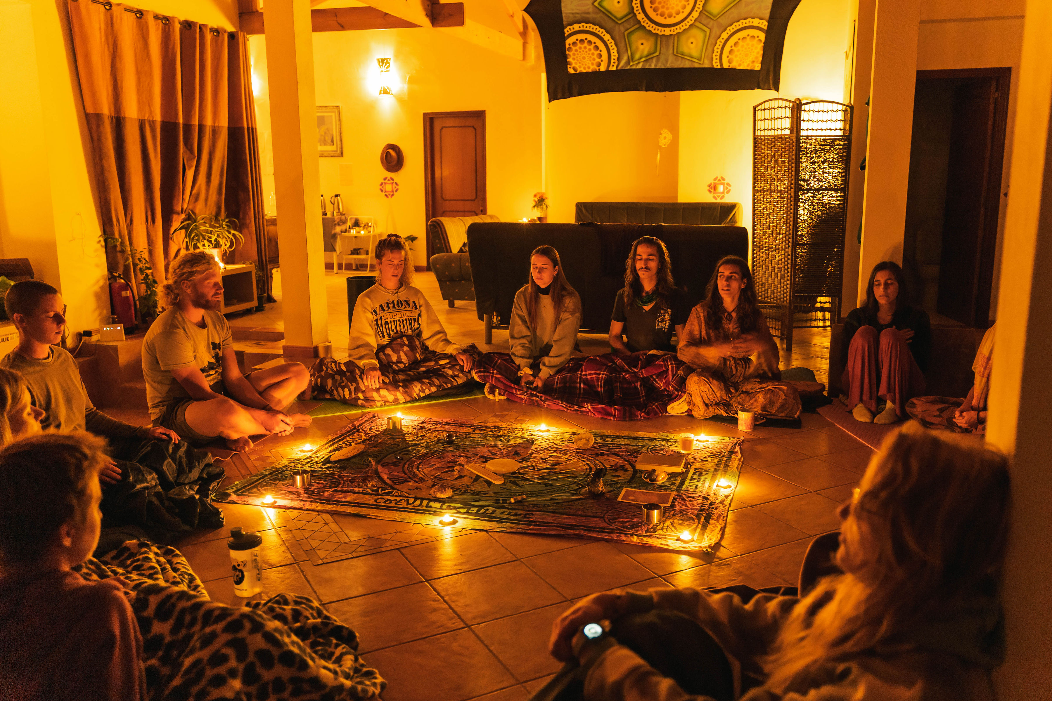 Group of people sitting in circle during a community gathering at night.