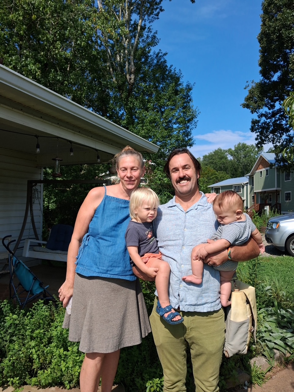 Family enjoying outdoor community event in a green neighborhood setting.