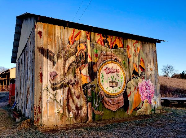Colorful mural on a wooden building promoting intentional community.