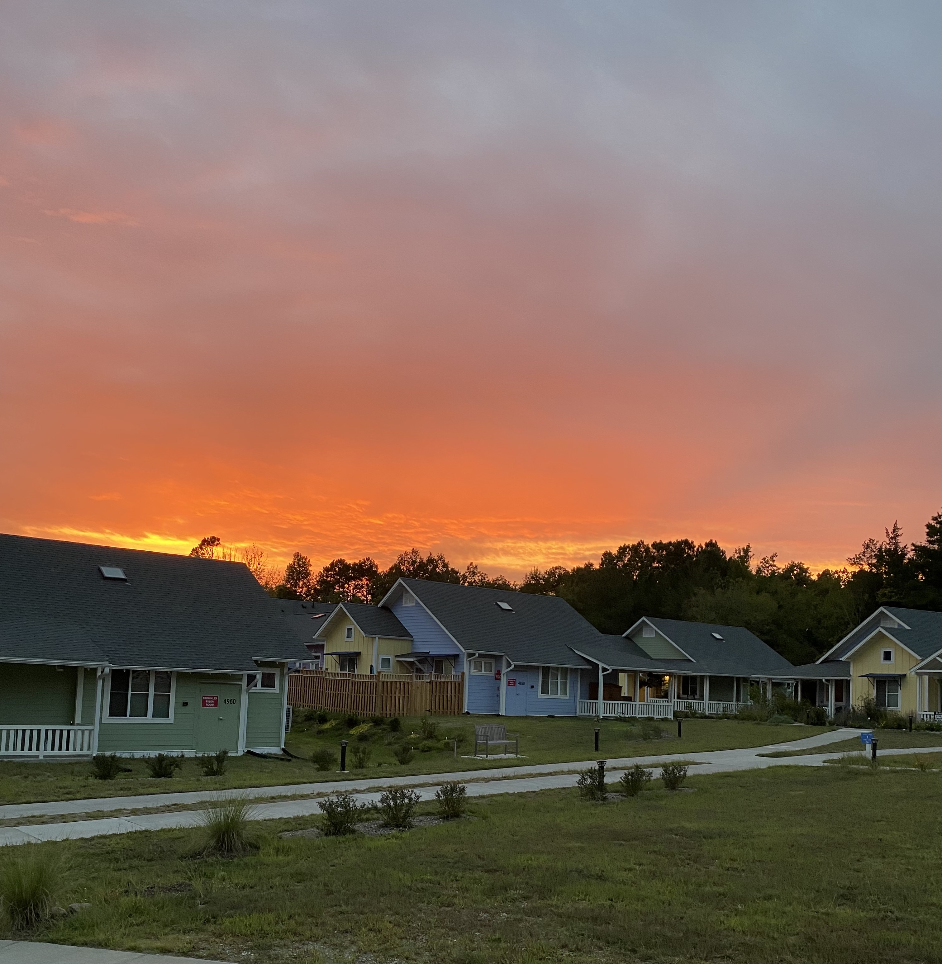 Colorful sunset over cohousing community with colorful houses and green lawns.