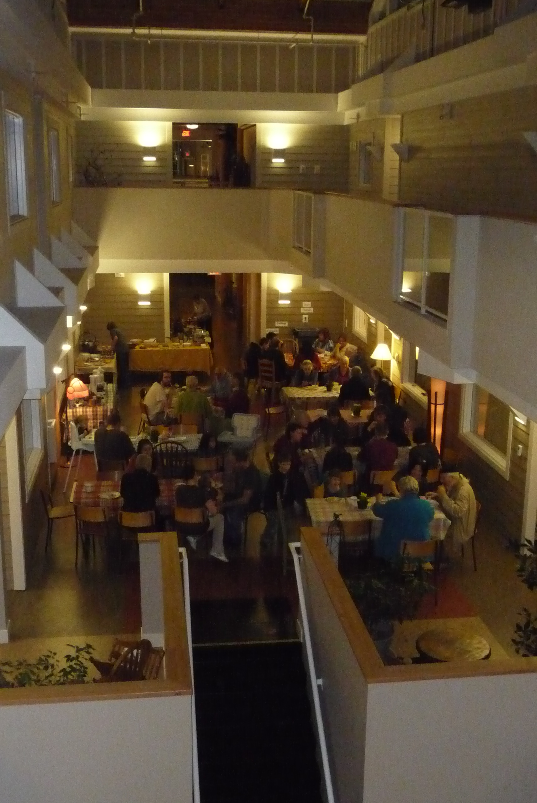 Indoor community event with people dining and socializing in a spacious hall.