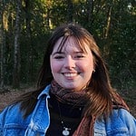 Smiling woman outdoors in a forest setting for intentional community.