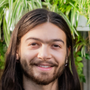 Person smiling with green plants in background at Foundation for Intentional Community.